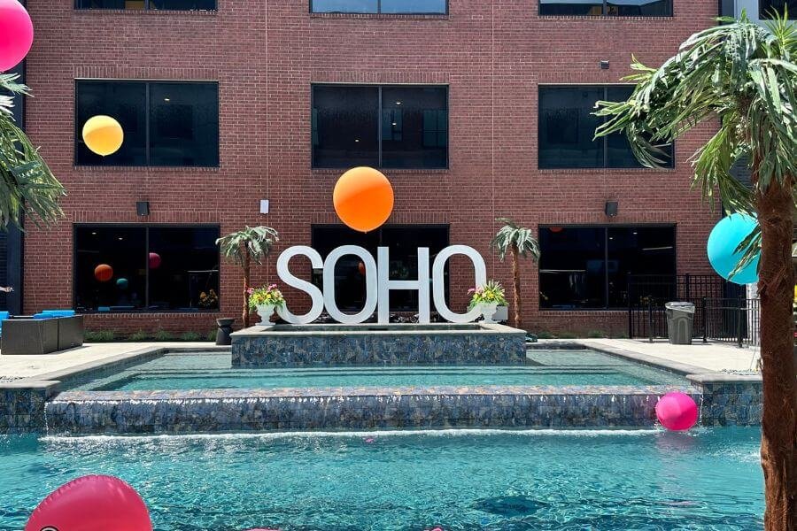 A captivating view of the luxurious poolside oasis at SoHo Apartments, with stylish lounge chairs, umbrellas, and sparkling blue water, creating the perfect setting for relaxation and summertime fun.